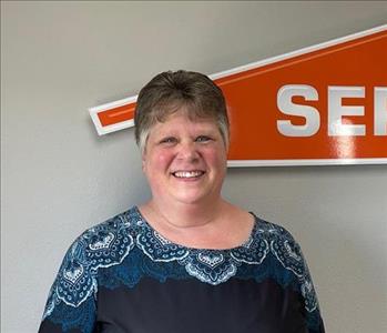 Female employee smiling in front of a SERVPRO sign