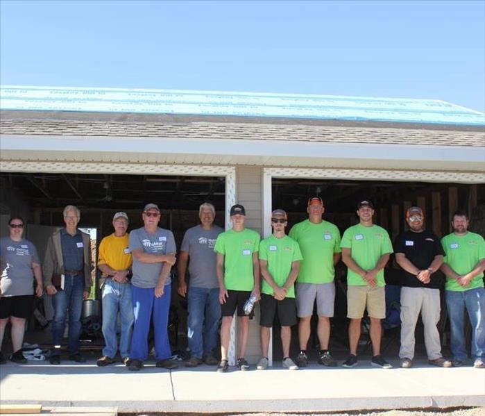Servpro and habitat crew in front of house