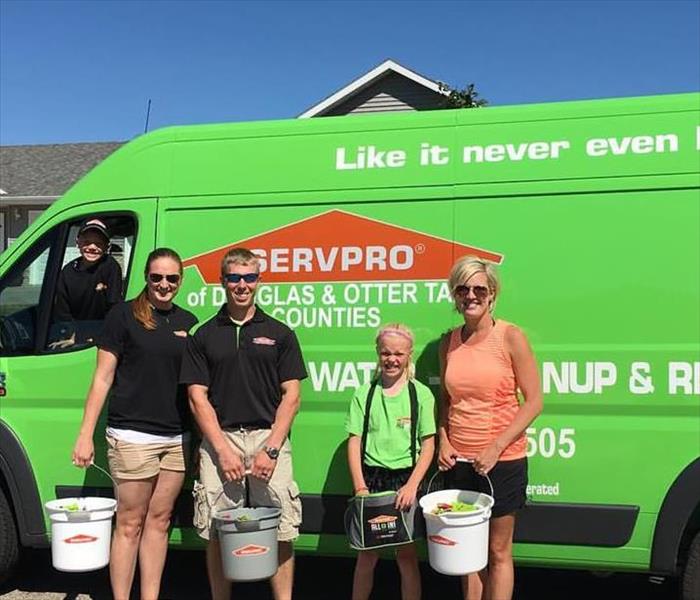 Four people standing in front of a SERVPRO van.